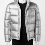 A man wearing a Custom Jackets USA metallic silver woven puffer jacket with horizontal quilting and a high stand collar against a clean white background.