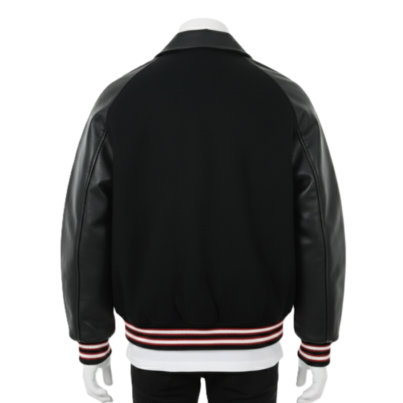 A man wearing a black and white leather varsity jacket with a wool body and snap buttons.
